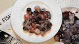 Fish eyeballs on a white plate with bowl of innards nearby; visible text E FISH