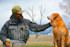 Angler in waders petting golden retriever with snow-capped mountains behind