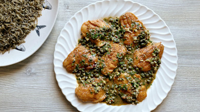 Pan-fried walleye piccata with caper-garlic sauce on white scalloped plate, wild rice