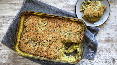 Baked potato gratin in a glass baking dish with golden breadcrumb crust and a plated slice