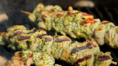 Grilled pheasant skewers with green herb marinade and char marks on grill