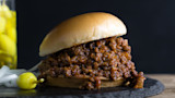 Venison sloppy joe sandwich on soft bun, served with pickled peppers and sliced onions