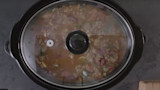 Slow cooker with venison chili simmering under a glass lid