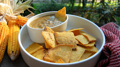 Bowl of corn salsa with tortilla chips and ears of yellow corn