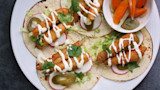 Four tacos with fried smelt, radish, pickled jalapeño, shredded cabbage, crema, cilantro
