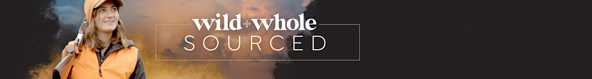 wild+whole SOURCED — woman in orange hunting vest and cap holding shotgun over shoulder