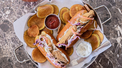 Fried fish po'boys with slaw, tartar sauce, ketchup, and round potato chips on tray