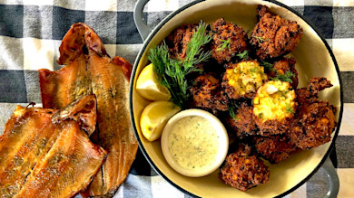 Smoked trout fritters with lemon, dill and creamy sauce; smoked trout fillets on checkered cloth