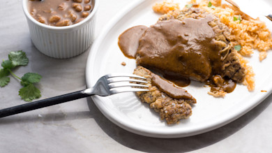 Chicken-fried venison steak with chili gravy, rice, beans in ramekin, fork