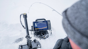 Humminbird fishfinder on ice showing sonar display, angler in hood at right