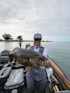 Angler holding large fish on boat; hat reads "CATCH FISH NOT FEELINGS"