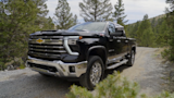 Black Chevrolet pickup truck on a gravel forest road