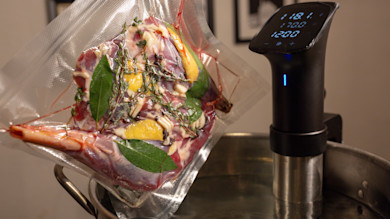 Vacuum-sealed leg of meat with lemon, garlic and herbs next to sous-vide 118°F