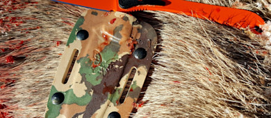 Blood-stained game hide with camouflage strap and orange plastic tag