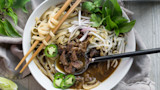 Venison shank pho in bowl with noodles, bean sprouts, basil, sliced jalapeño and chopsticks