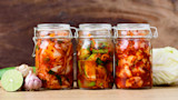 Three glass jars of kimchi with lime, garlic, ginger and napa cabbage