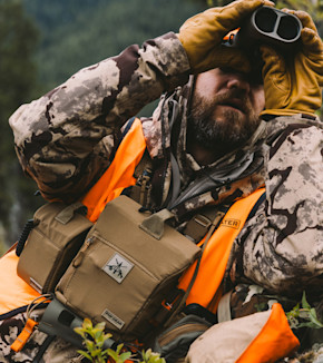 Hunter in camouflage and orange vest using binoculars, tan bino pack with FHF GEAR patch