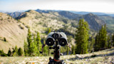 Vortex binoculars on a tripod overlooking a sunlit mountain valley