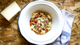 Chanterelle gnocchi in white bowl with cherry tomatoes and grated cheese; cheese block beside