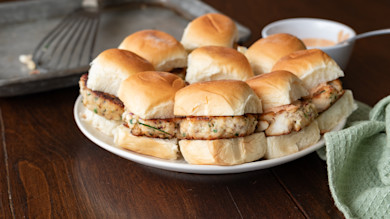 Catfish sliders on soft rolls arranged on a plate with a bowl of dipping sauce