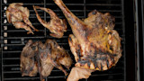 Spatchcocked game birds on a grill grate — three small birds and one large split bird