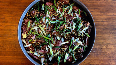 Venison tataki in ponzu sauce topped with sliced scallions and minced garlic