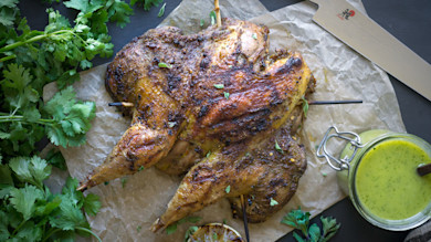 Spatchcocked roasted pheasant on parchment with cilantro and a jar of Cuban mojo sauce