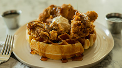 Waffle topped with fried pheasant, a dollop of butter and syrup drizzle