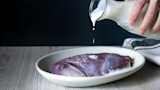 Raw wild game on plate with milk being poured over it