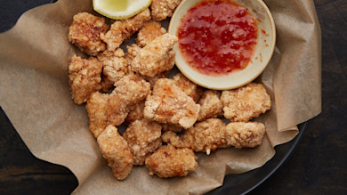Breaded popcorn-style fish bites with lemon wedge and sweet chili dipping sauce
