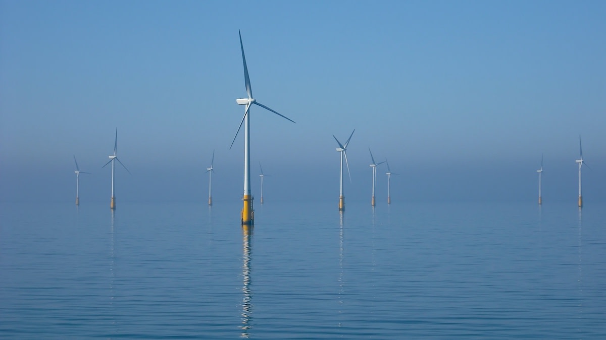 Offshore wind farm with turbines reflected in calm blue sea