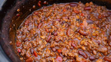 Thick chili with ground meat, kidney and pinto beans simmering in a cast-iron pot