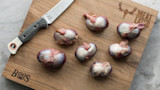 Raw gizzards on wooden cutting board with knife, visible text "MEAT EATER" and "Boos 1887"