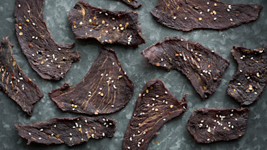 Thai-chili jerky slices with sesame seeds and red pepper flakes on dark slate