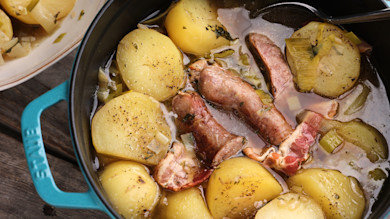 Dublin coddle stew with potatoes, sausages, bacon, and leeks in turquoise pot; handle reads 'STAUB'
