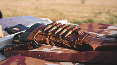 Rifle stock with leather cartridge holder holding six cartridges on camouflage cloth