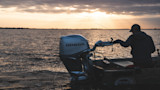 Angler fishing from small boat at sunset with outboard labeled HONDA