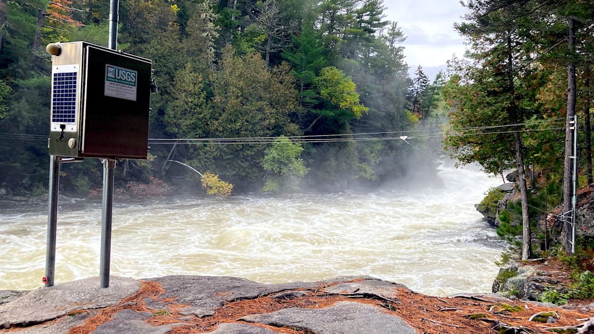 Rushing whitewater river with mist and USGS monitoring box on metal poles