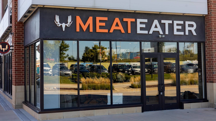 MEATEATER storefront with antler skull logo above glass windows reflecting parked cars