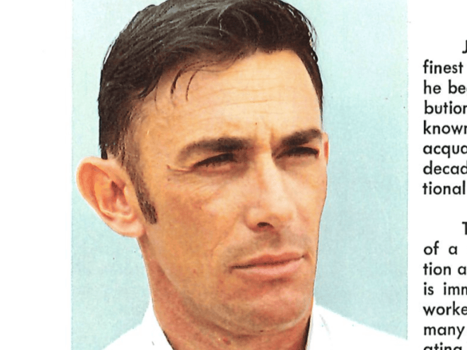 Close-up portrait of a man with short dark hair looking right against pale blue background
