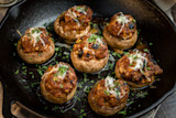 Venison-stuffed mushrooms with melted cheese and chopped herbs in a cast-iron skillet