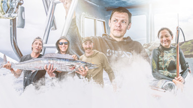 Man in hoodie with "FIRST LITE" text on boat, group holding a large fish