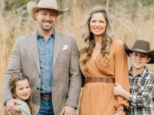 Family portrait: man, woman, girl and boy in cowboy hats standing in tall grass