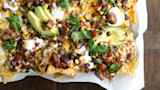 Venison nachos with black bean and corn salsa, sliced avocado, melted cheese, sour cream, cilantro