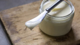 Jar of tallow-butter with knife holding a smear on wooden cutting board