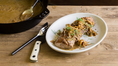 Hog loin topped with caramelized onions and fennel on a white plate