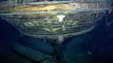 Underwater wooden ship bow with sea anemones and hull text 'MOUNTNCE'