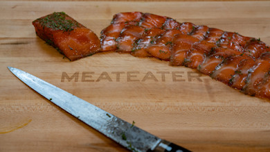 Sliced gravlax and fillet with carving knife on cutting board reading MEATEATER