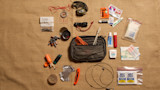 Hunting utility kit flat lay with pouch, compass, headlamp, batteries, knife, "SOG Bits" bag and Wet Ones