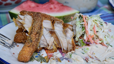 Fried carp fillets with coleslaw and a watermelon slice on a plate